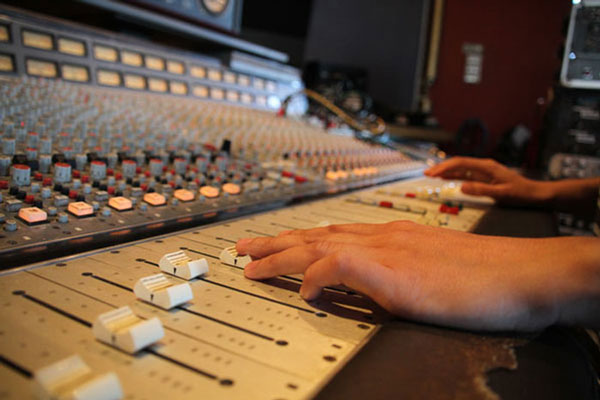image of mixing console with engineer pushing up faders